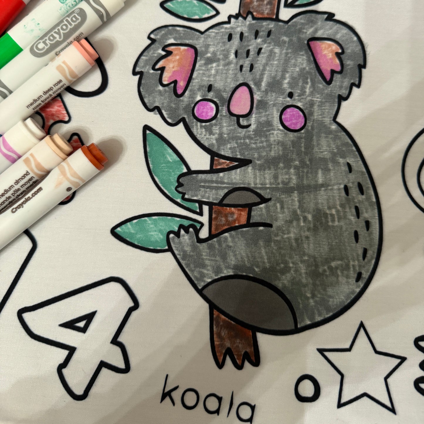 fabric coloring tablecloth for preschool aged kids with a koala illustration and markers on a white background