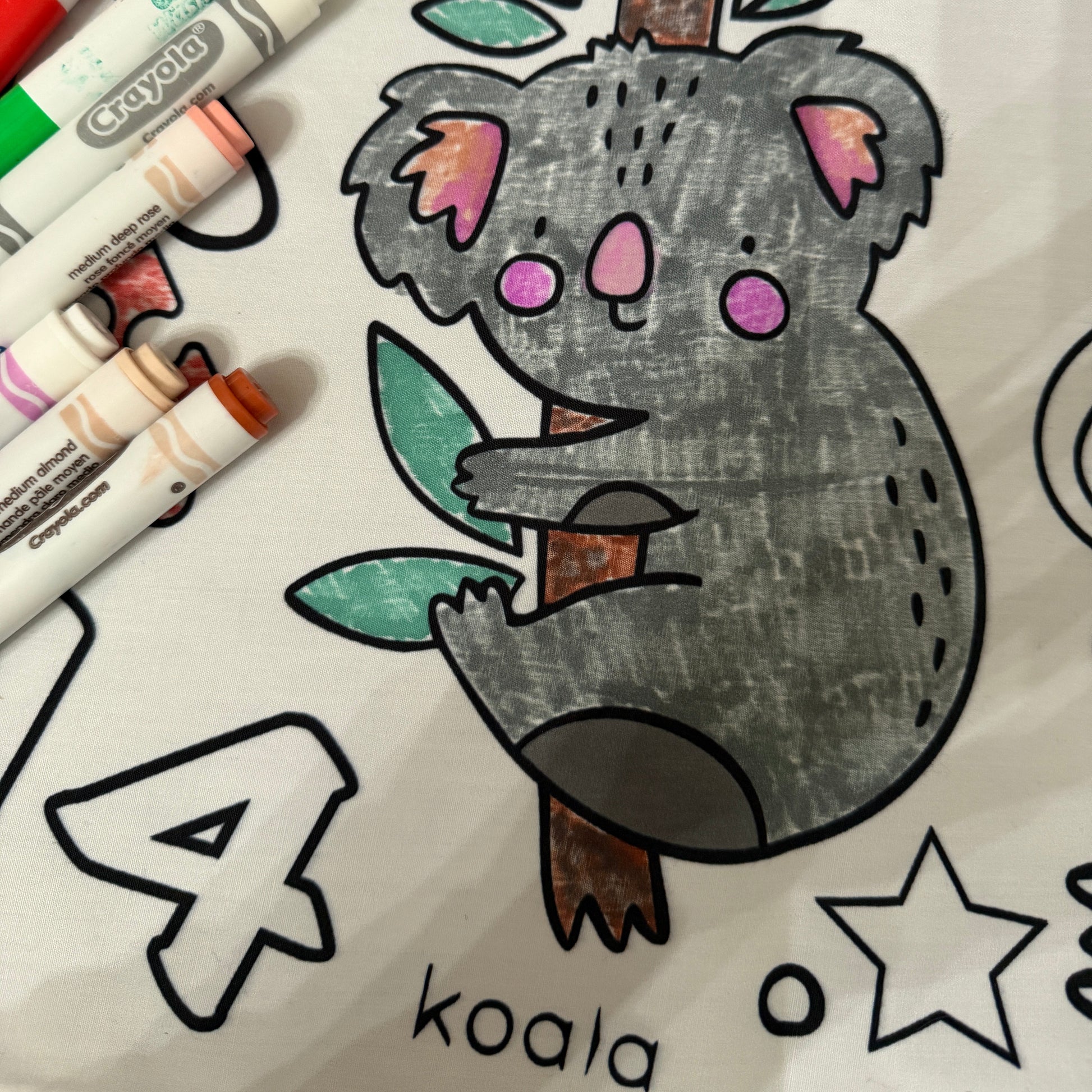 fabric coloring tablecloth for preschool aged kids with a koala illustration and markers on a white background