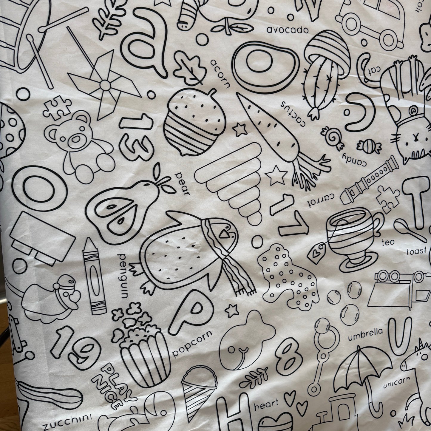 White fabric coloring tablecloth with black line preschool art patterns including numbers, animals, and objects.