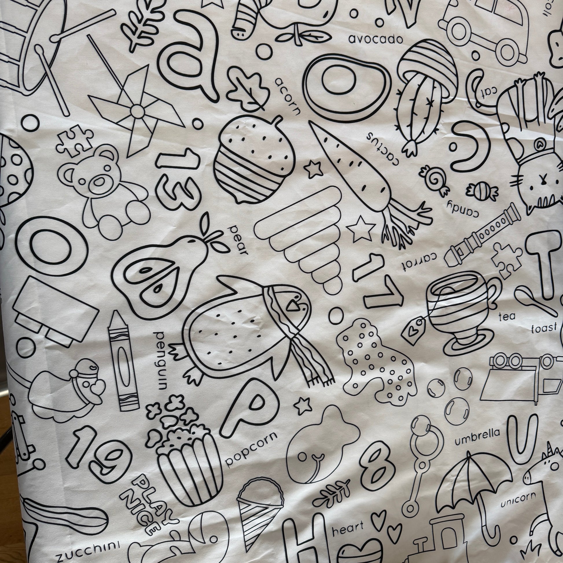White fabric coloring tablecloth with black line preschool art patterns including numbers, animals, and objects.