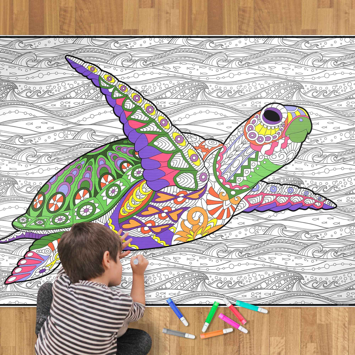 A child coloring a large sea turtle coloring poster with colored markers.  The poster is black line graphics in wavy background patterns and a swimming sea turtle covered in exciting patterns. The child is shown from behind, wearing a striped shirt, and the scene is set on a wooden floor.