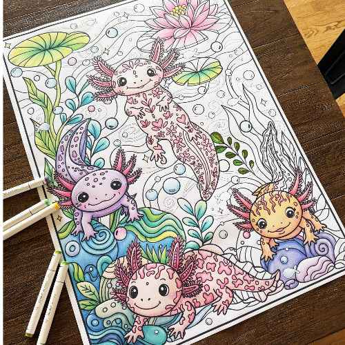A coloring poster featuring four cute axolotl illustrations with lily pads and bubbles, placed on a dark wooden table with colored pencils visible at the lower left.  Poster by Artistic Chaos ink.