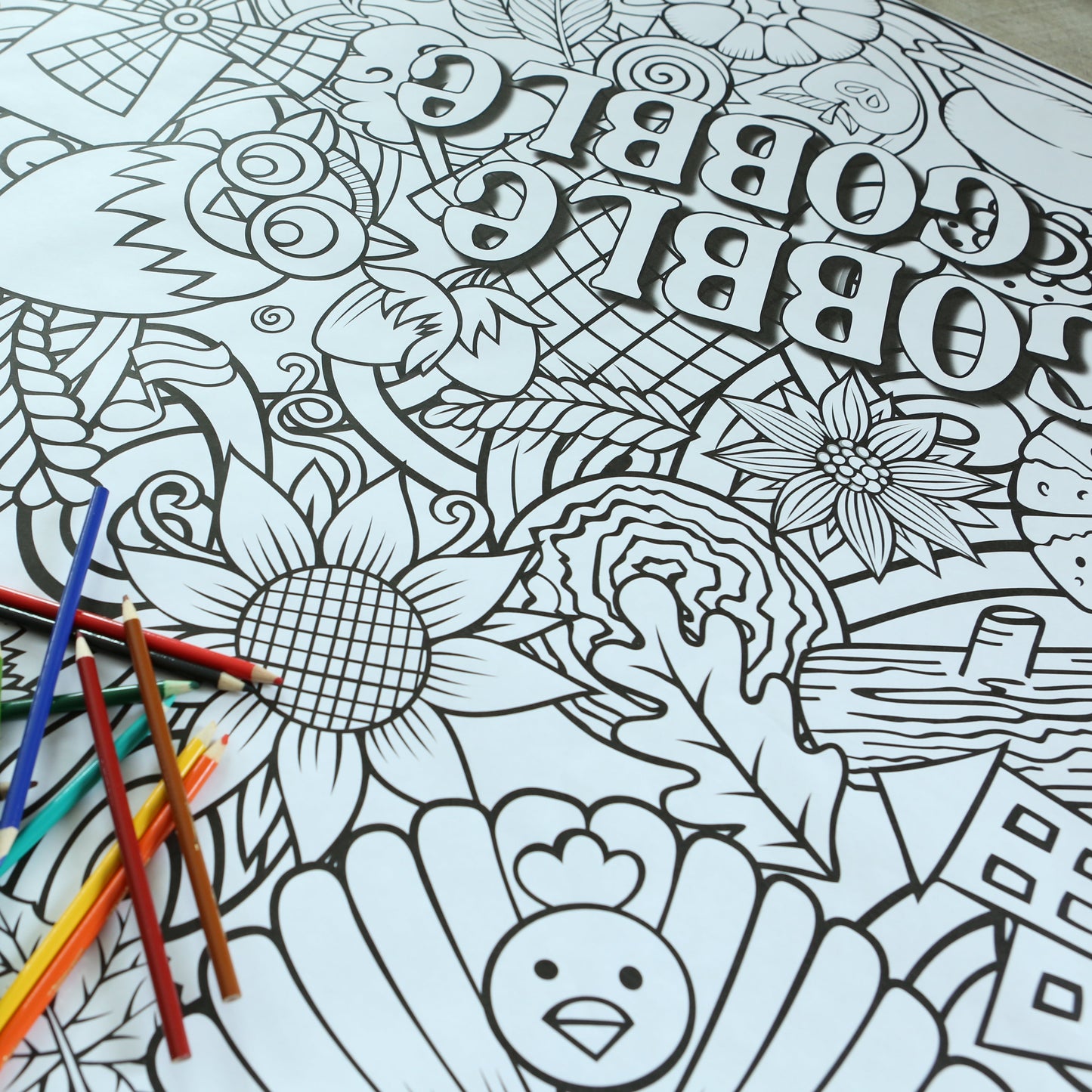 Thanksgiving Coloring sheet with intricate thanksgiving and fall designs and coloring pencils on a table.