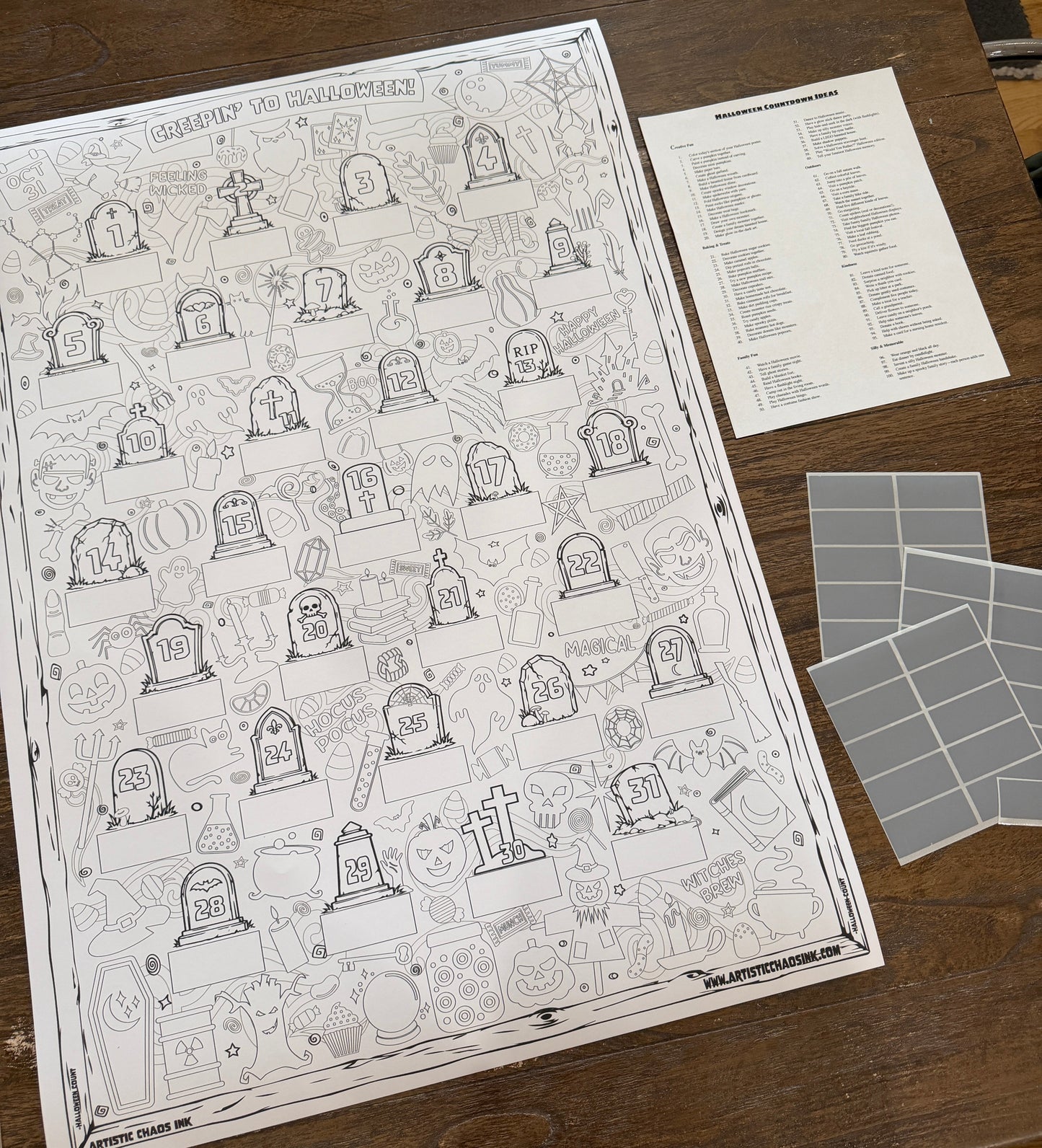A Halloween-themed bingo board game set displayed on a wooden table, featuring a large black-and-white illustrated bingo board, a list sheet, and gray bingo tiles.
