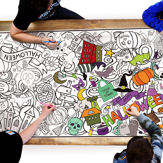 group of people coloring a halloween themed coloring sheet on a table