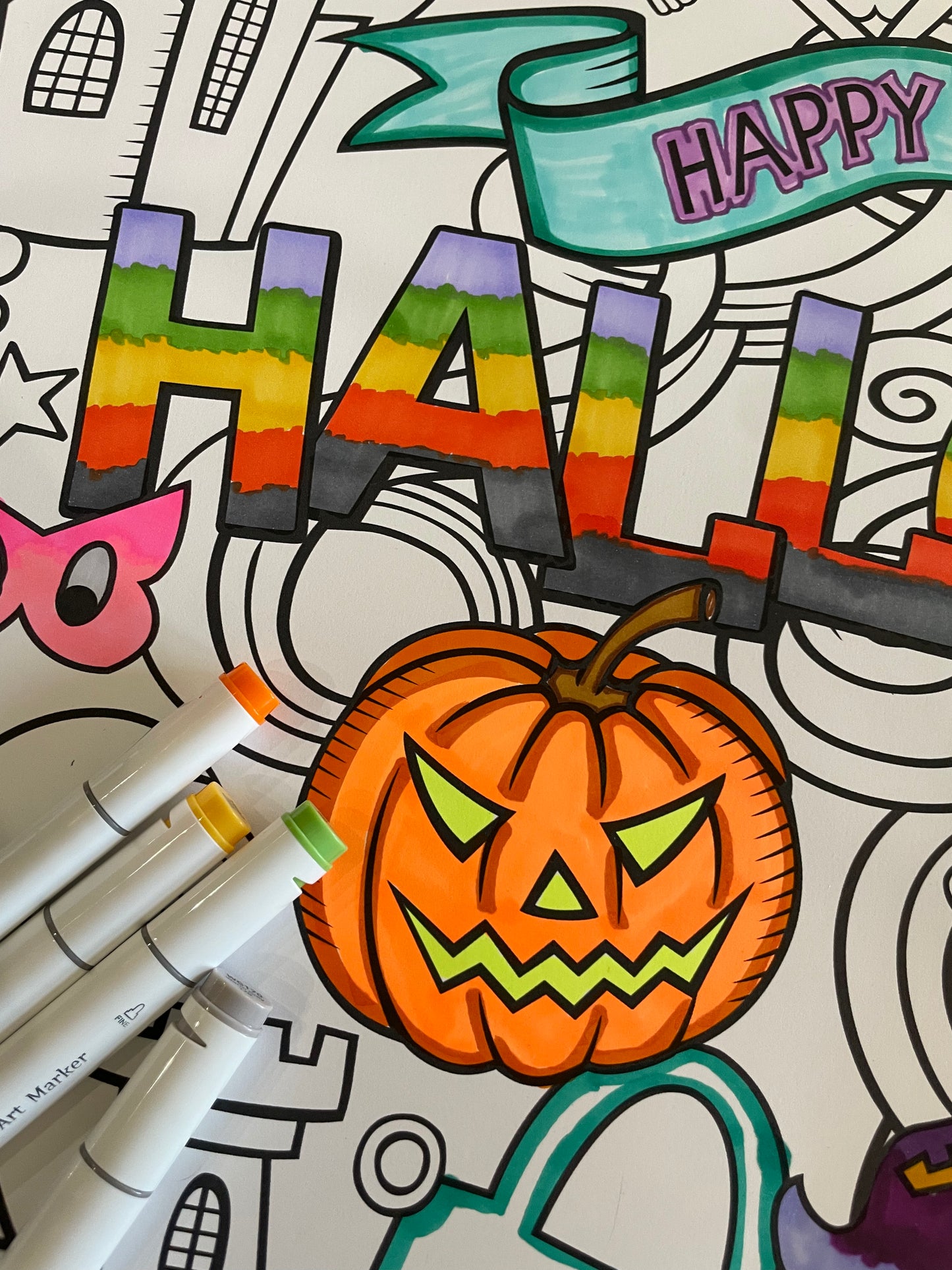 Coloring page with a pumpkin, 'Happy Halloween' text, and markers on a white background