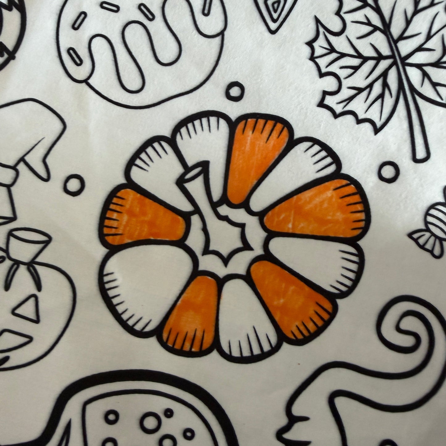 Decorative pattern with orange pumpkin-like shapes and black leaf outlines on a white fabric tablecloth background