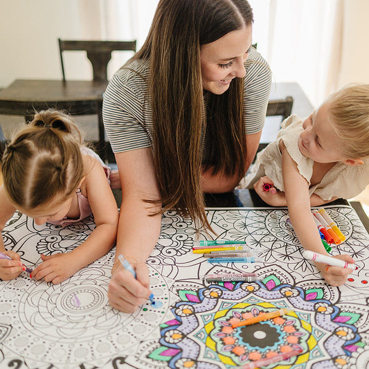 Two children and a woman coloring at a table on a mandala everyday event banner by artistic chaos Ink.