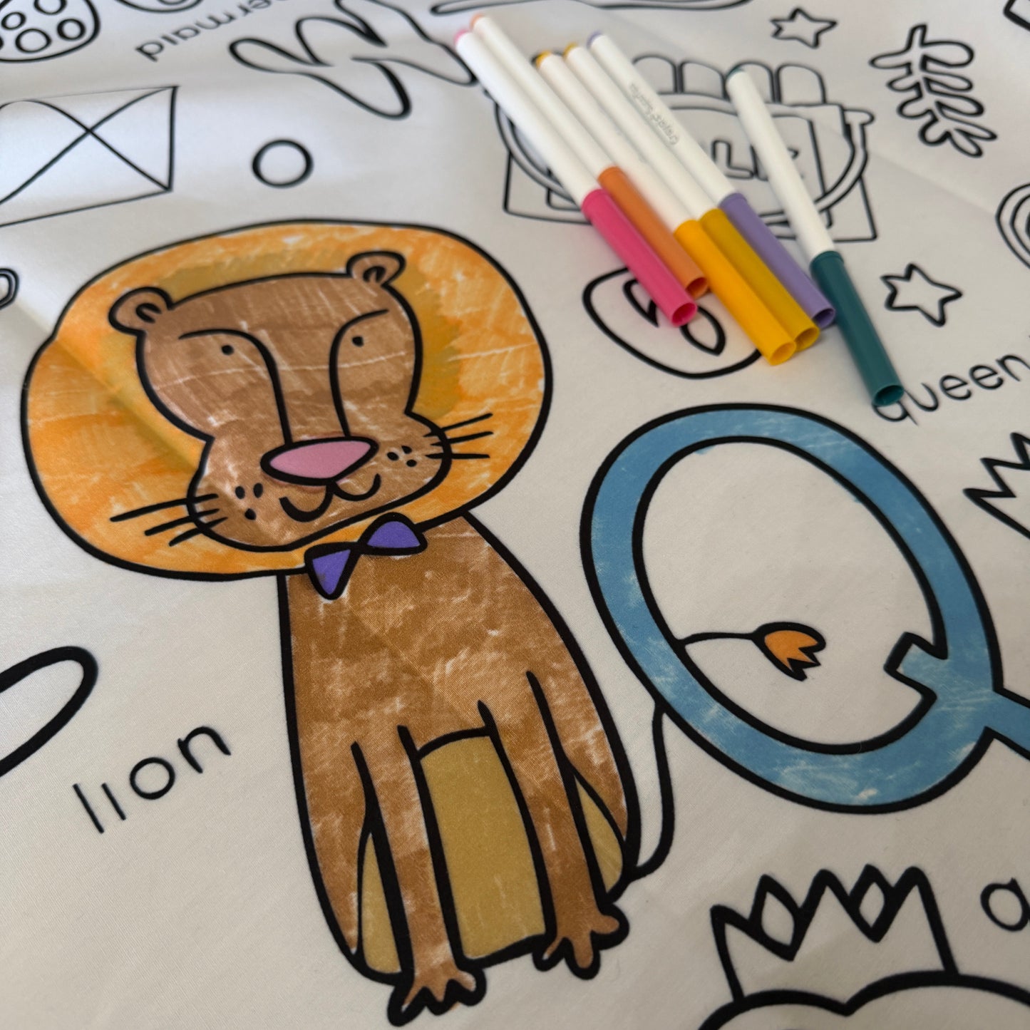 Coloring fabric tablecloth with a colored lion illustration and markers on a white background