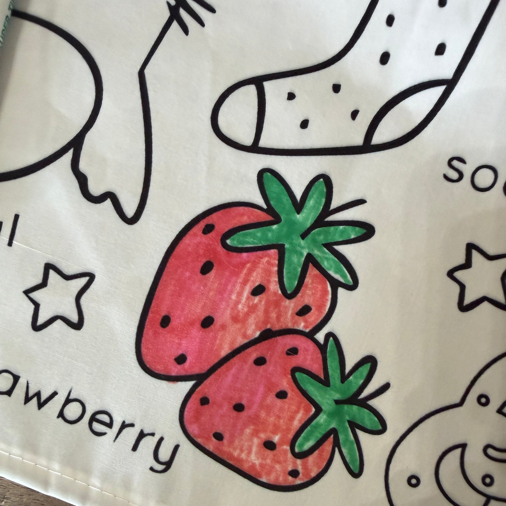 Coloring tablecloth with colored strawberries and black outlines on a white fabric tablecloth