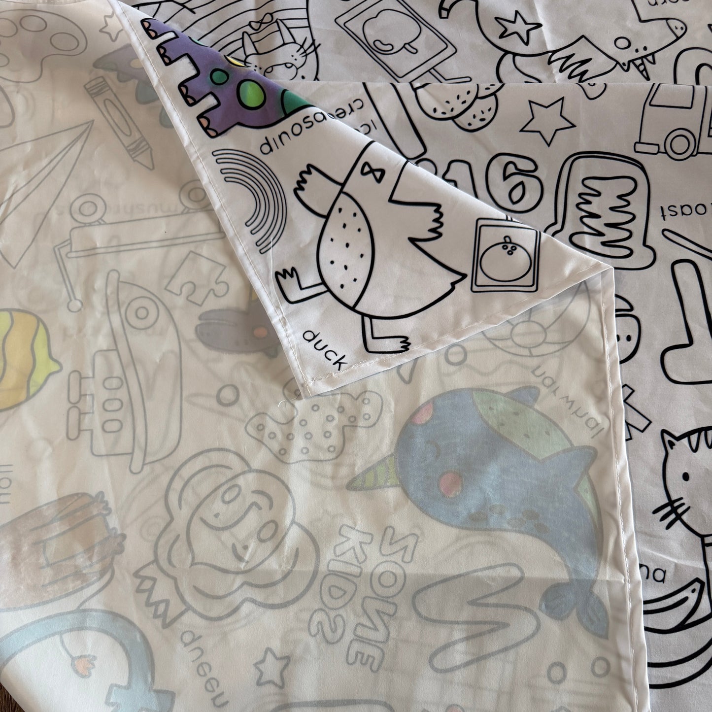 Children's coloring tablecloth with cartoon character patterns on a wooden surface