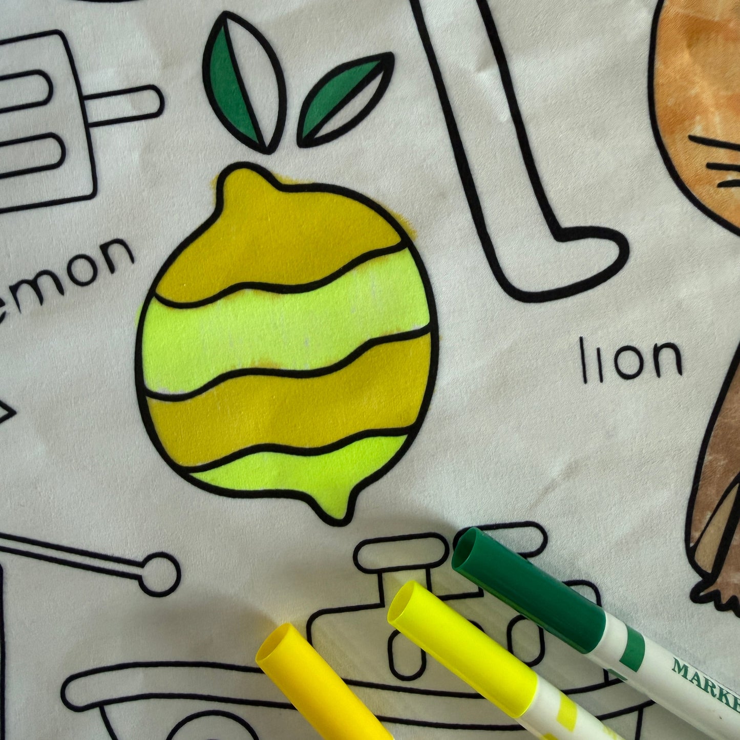Coloring tablecloth with lemon illustration and markers on a white background
