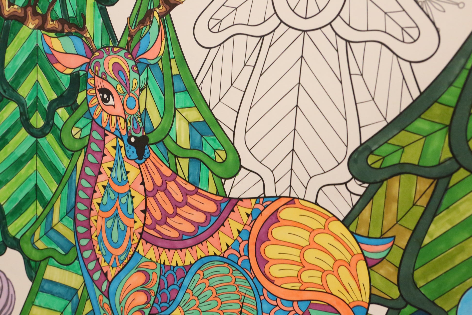 Colorful reindeer illustration with intricate patterns on a green Christmas tree background