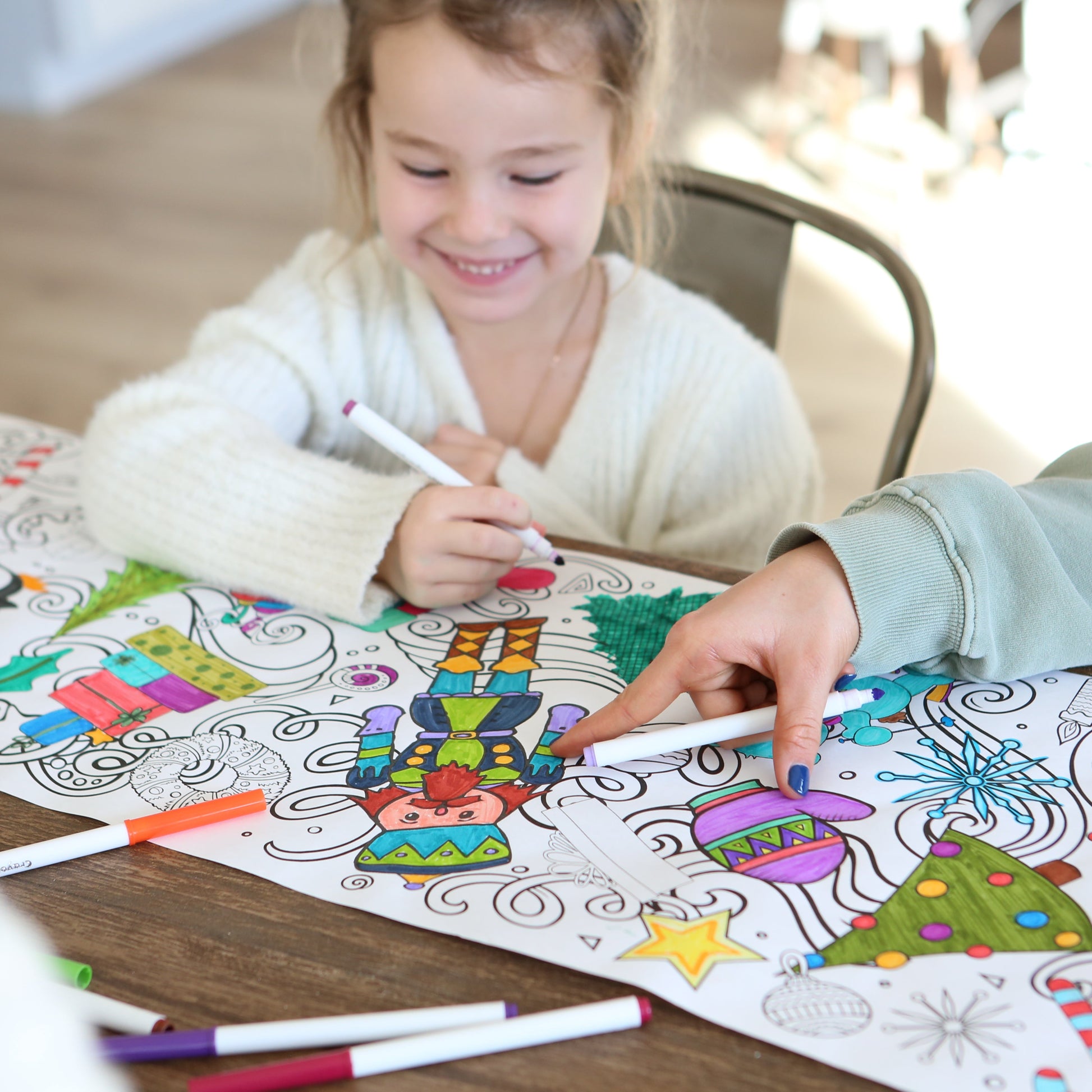 Little girl coloring a nutcracker with an older girl pointing to it. 