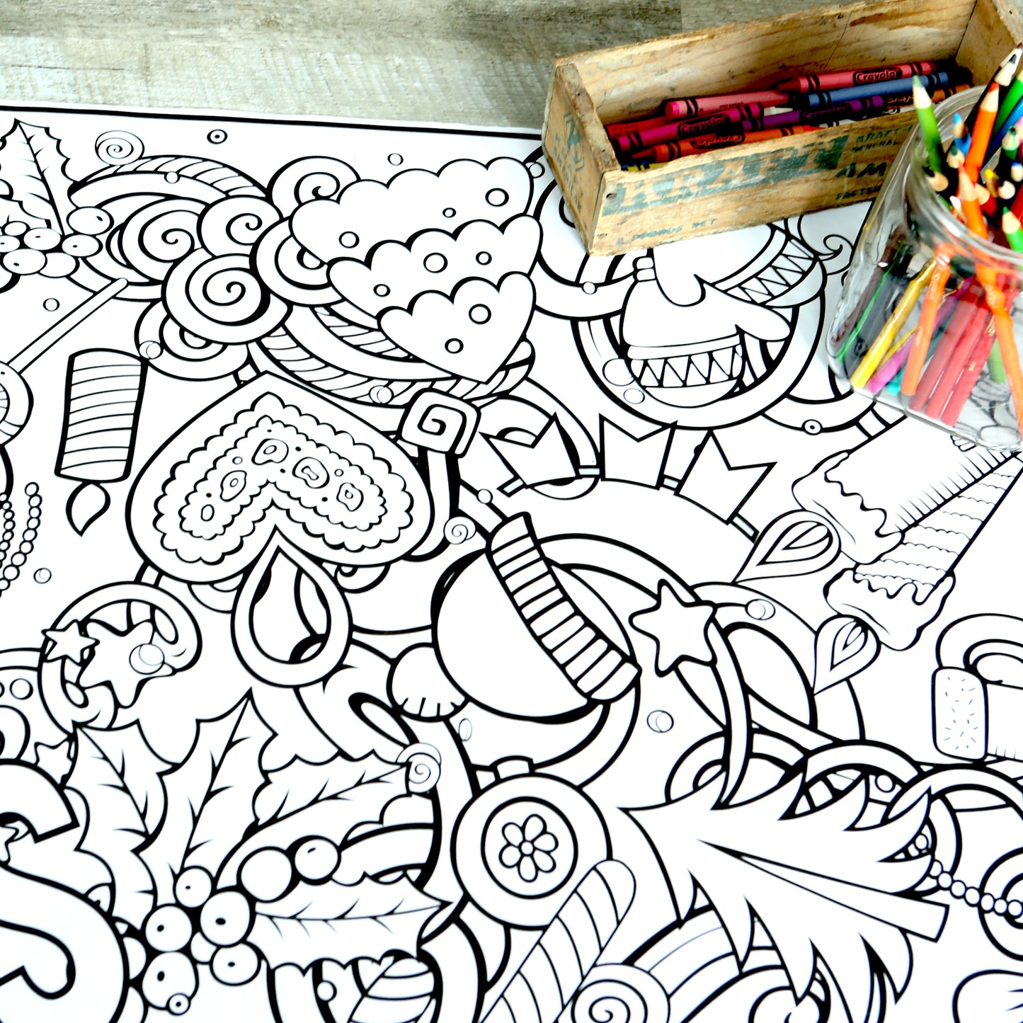 Coloring banner with Christmas designs all over it. Holly berries, a Christmas tree, candles, a star, hearts, ornaments and a box of colored pencils.
