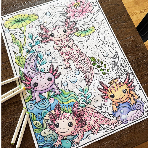 A colorful axolotl coloring page laid on a dark wooden table, with three colored pencils resting on the left side. The page features four cute axolotl illustrations with various pastel colors like pink, purple, green, and blue, set against an underwater scene with lily pads and bubbles.