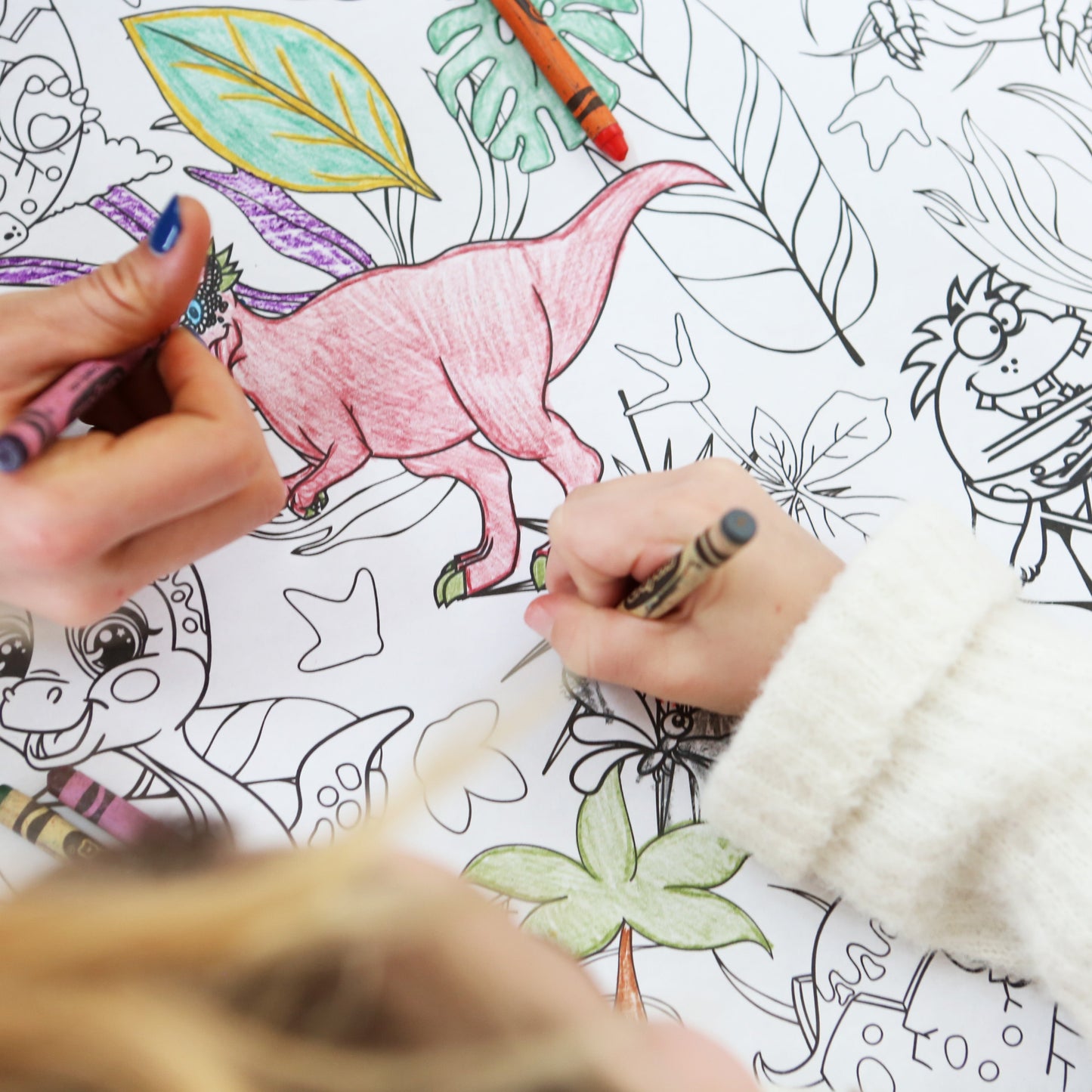 Two hands coloring a dinosaur on an adult coloring poster with crayons.