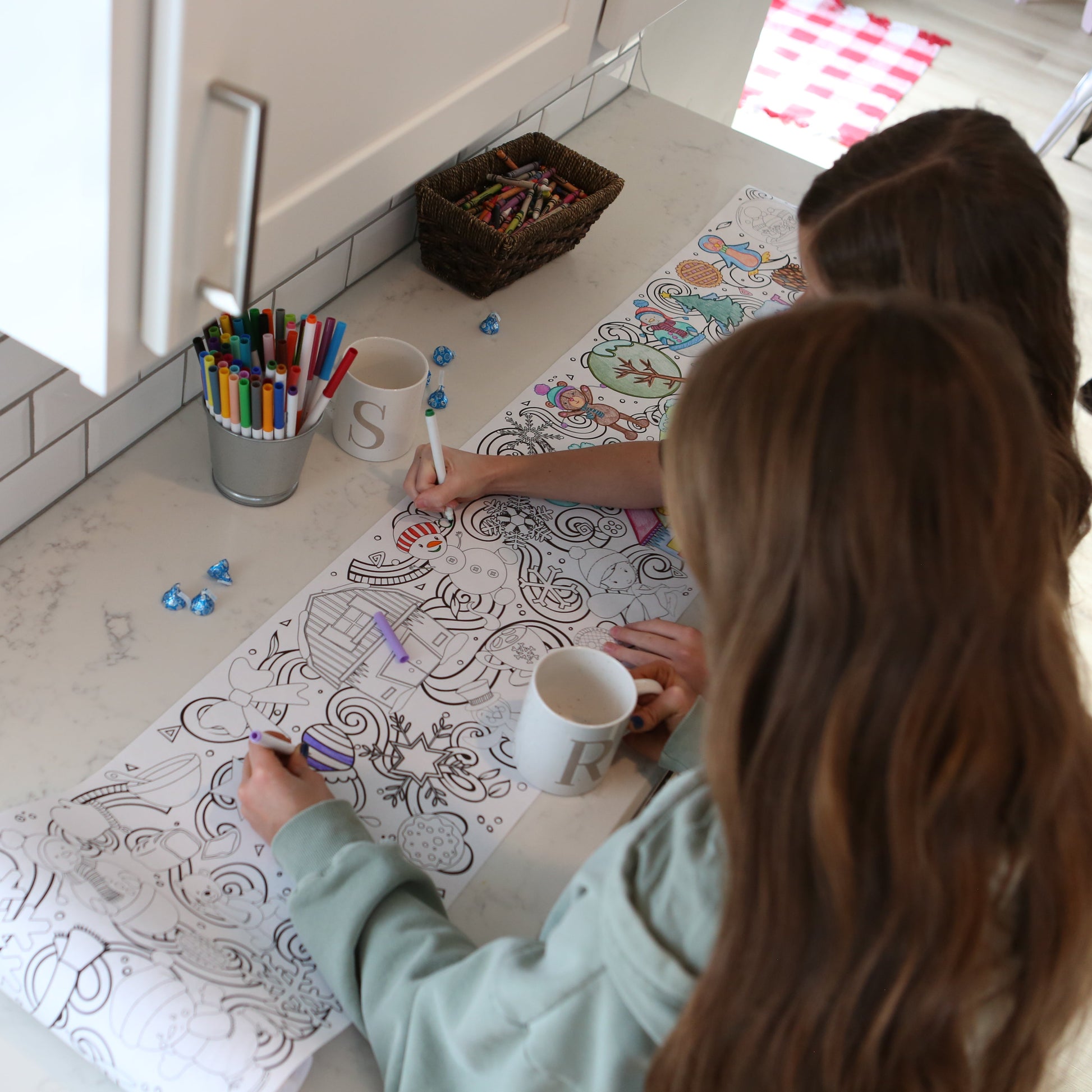 girls coloring a winter scene with cups of hot chocolate