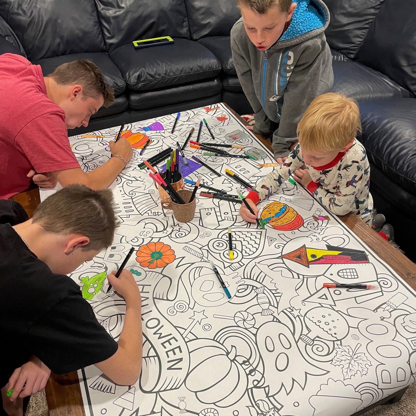 Children coloring on a table with Halloween-themed coloring poster