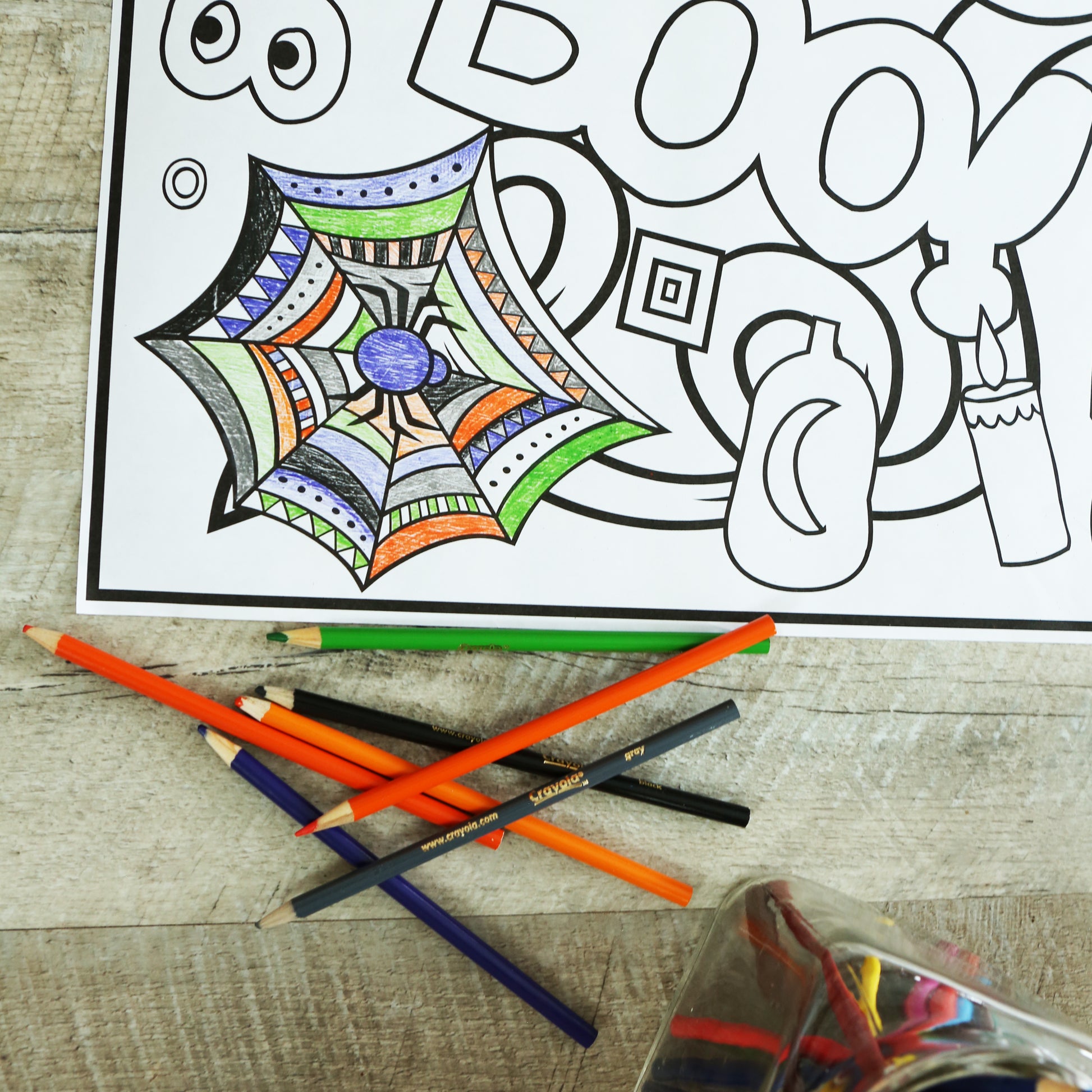 part of a coloring sheet where the spider web has been colored with bright colored pencils