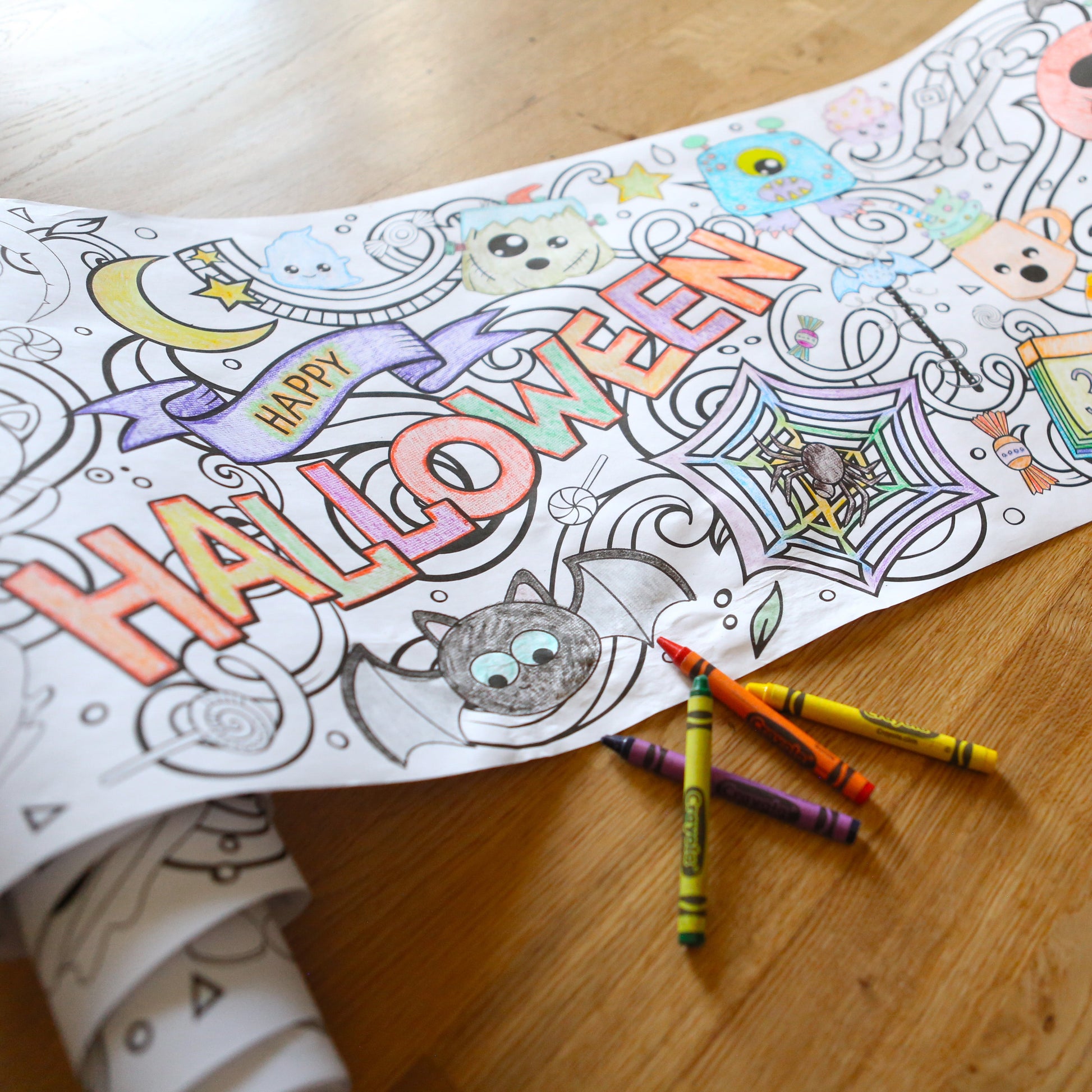 Happy Halloween coloring banner with small pile of crayons on a wood floor
