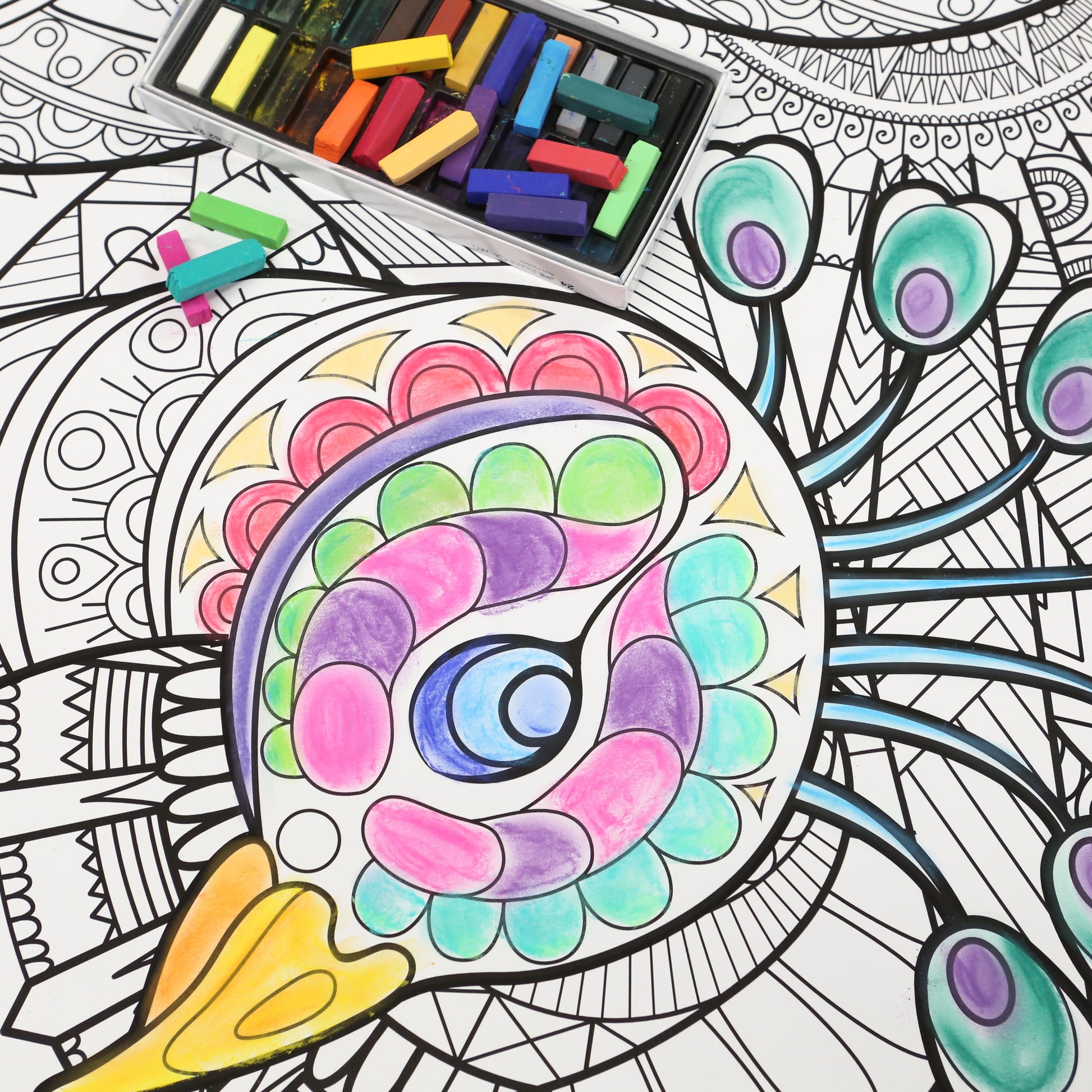 brightly colored peacock with a box of chalk pastels sitting near it. 