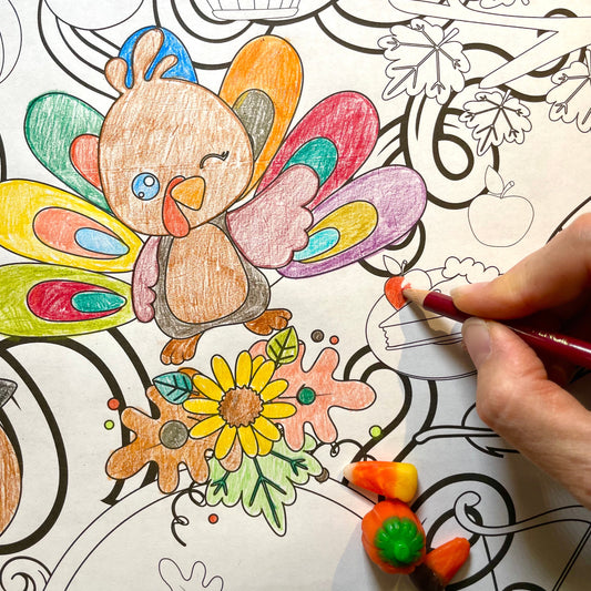 Coloring banner page with a turkey and autumn-themed illustrations, being colored by a hand.