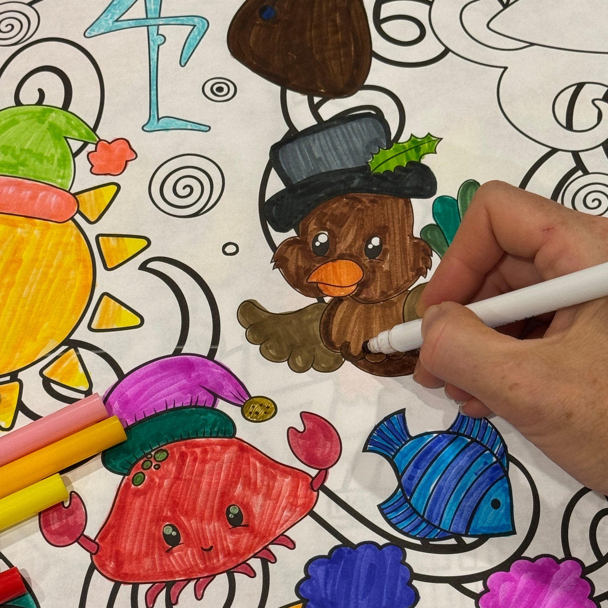 Coloring banner with various tropical christmas animals and a hand using a marker to color one of them.